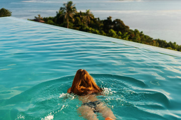 girl in the pool at sunset with views of the mountains and the sea