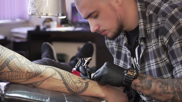 Tattoo master draws a tattoo on the man's hand