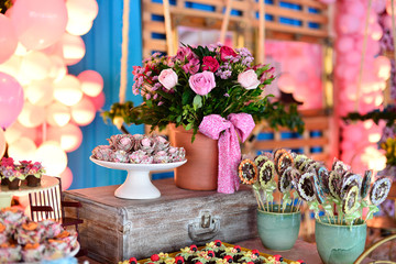 candy table decorated in light tones flowers and pink balloons