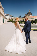 Beautiful young bride with her handsome groom walking in palace Belvedere