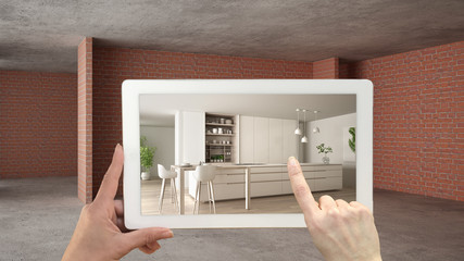 Fototapeta na wymiar Augmented reality concept. Hand holding tablet with AR application used to simulate furniture and design products in interior construction site, modern kitchen with island and stools