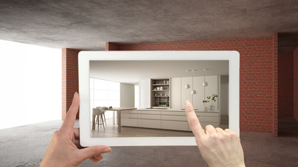 Augmented reality concept. Hand holding tablet with AR application used to simulate furniture and design products in interior construction site, modern kitchen with island and stools