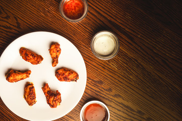 Chicken wings, beer, and dipping sauce on wooden table.
