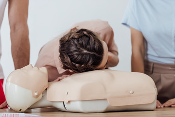 woman practicing cpr on dummy during first aid training class
