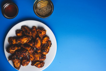 Chicken wings, dipping sauce and beer on blue background.