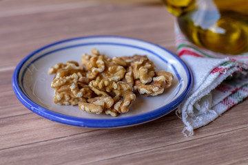 Healthy peeled nuts on a ceramic plate accompanied by a bottle of extra virgin olive oil.