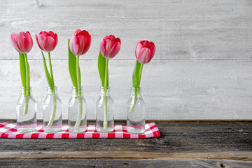 Frische Tulpen in Vasen vor Holzhintergrund