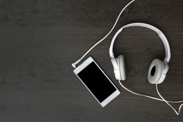 white headphones and a white smartphone on a wooden table