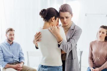 selective focus of women hugging during group therapy session