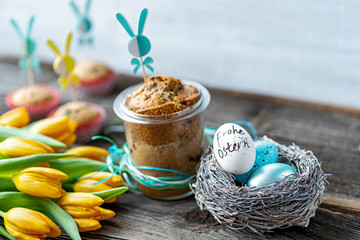 Osternest mit Osterei, Tulpen und Kuchen im Glas