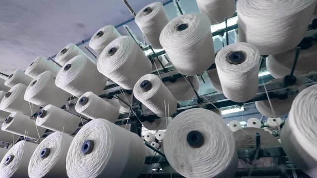 Textile plant machine spooling threads onto bobbins. Industrial fabric production line