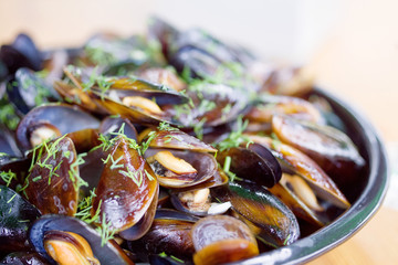Cooked mussels with greens on a plate, seafood, soft focus