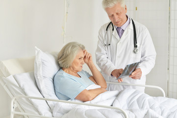 Obraz premium Portrait of sad senior woman in hospital with caring doctor