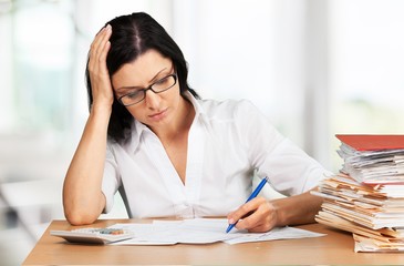 Businesswoman sitting at the table with many papers in office