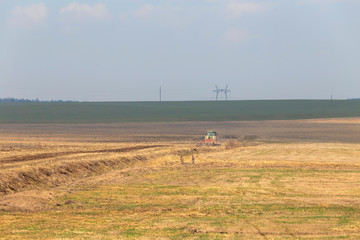 tractor plows the field in early spring for sowing crops. Agriculture of Belarus.