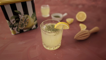 Homemade lemonade with mint and ice, served with fresh lemons on orange table. Food and drink frame