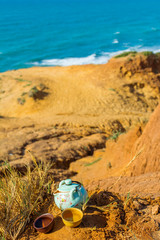 Chinese tea ceremony with porcelain teapot with lotus, clay cups. View of nature beach landscape with blue sea on a sunny day.