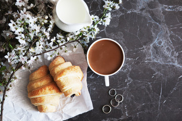 concept of morning breakfast. Fresh croissant and a cup of hot coffee with milk.