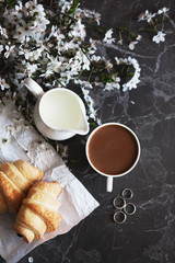 concept of morning breakfast. Fresh croissant and a cup of hot coffee with milk.