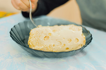 boy of European appearance sits at the table and has breakfast, he eats dairy products with a fork and makes emotions. Food concept