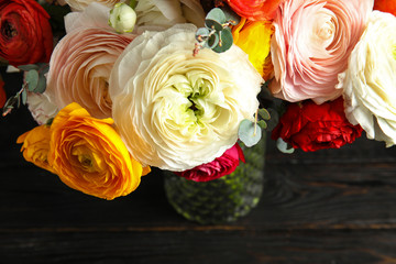Bouquet with beautiful bright ranunculus flowers on dark table, view from above