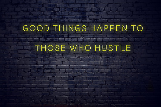 Positive inspiring quote on neon sign against brick wall good things happen to those who hustle