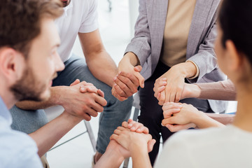 cropped view of people holding hands during group therapy session