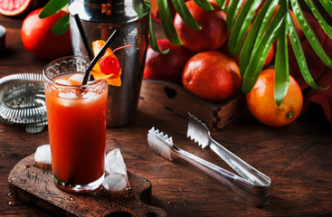 Summer refreshing low alcoholic cocktail with vodka, orange juice, bloody orange and ice cubes. Wooden table. Selective focus. Copy space