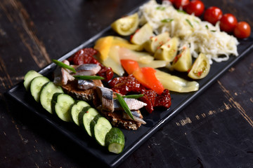 set of pickled vegetables and fish on a dark plate