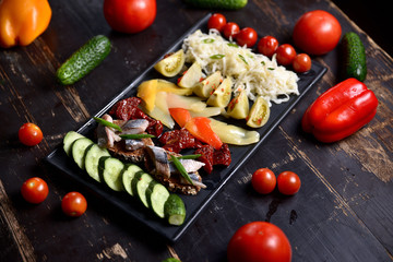 set of pickled vegetables and fish on a dark plate