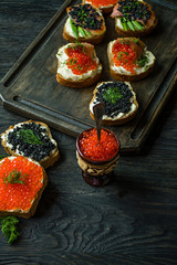 Red caviar in pottery. Close-up. Dark wooden background.