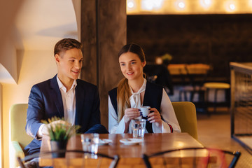 A stylish couple drinks morning coffee at the cafe, young businessmen and freelancers