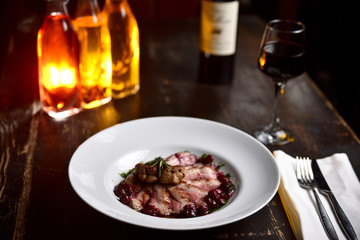 fried duck meat with berry sauce on a white plate