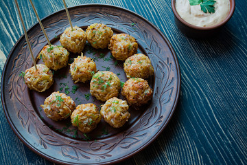 Vegetarian croquettes of potatoes and cabbage with sauce, vegetables and herbs. Packed in parchment. Tasty and satisfying. Dark wooden background. Side view.