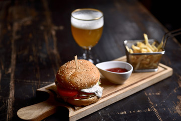 burger with french fries and beer on a wooden board