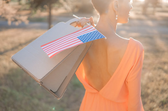 Memorial day sale, Independence day sale. Female hand with paper bag and american flag in spring or summer park