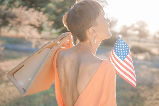 Memorial day sale, Independence day sale. Female hand with paper bag and american flag in spring or summer park