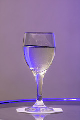 water in glass on the table with purple light