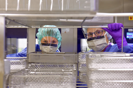 Two women work in a hospital as medical hygiene  technicians. They are dressed in special medical  hygiene clothing. They are seen carrying out hygiene  disinfecting and sterilization tasks.