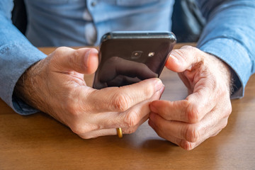 man's hand holding a phone at the table