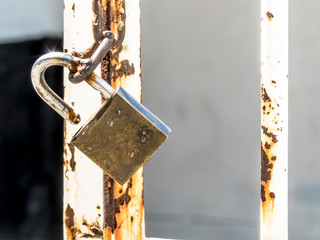 Open padlock hanging on a rusty chain