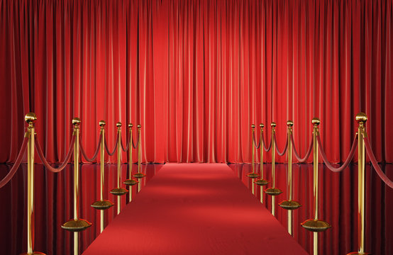 Theater stage with red velvet curtains and event carpet with golden barrier. 