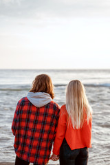 Young couple on beach looking at sunset. Staying seaside on vacation. Back view.