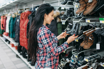 Young woman choosing shoes in supermarket