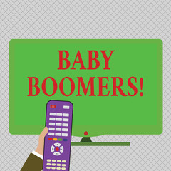 Conceptual hand writing showing Baby Boomers. Concept meaning demonstrating who is born in years following Second World War Hand Holding Remote Control infront of Wide Color PC Screen