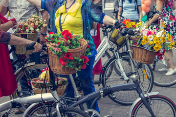 Fototapeta na wymiar Bicycles with baskets of flowers. Women in bright clothes hold the handlebars