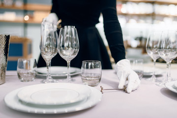 Waitress in gloves puts the dishes, table setting