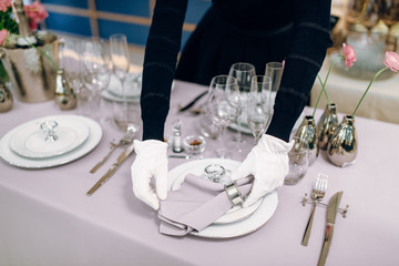 Waitress prepares tablecloth, table setting
