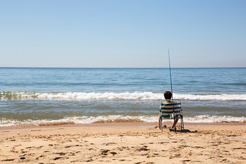 Niño pescando en la orilla de la playa.