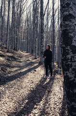 Lonely Girl hiking in the forest with a stick